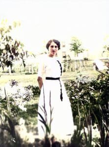 A woman dressed in white standing amongst a garden of flowers.