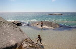 Rocks and water one climbing the rocks, one sunbathing the other just standing.