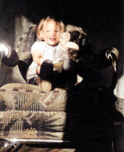 Child sitting on chair holding a doll.