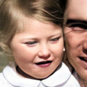 Child's face looking satisfied with man holding her.